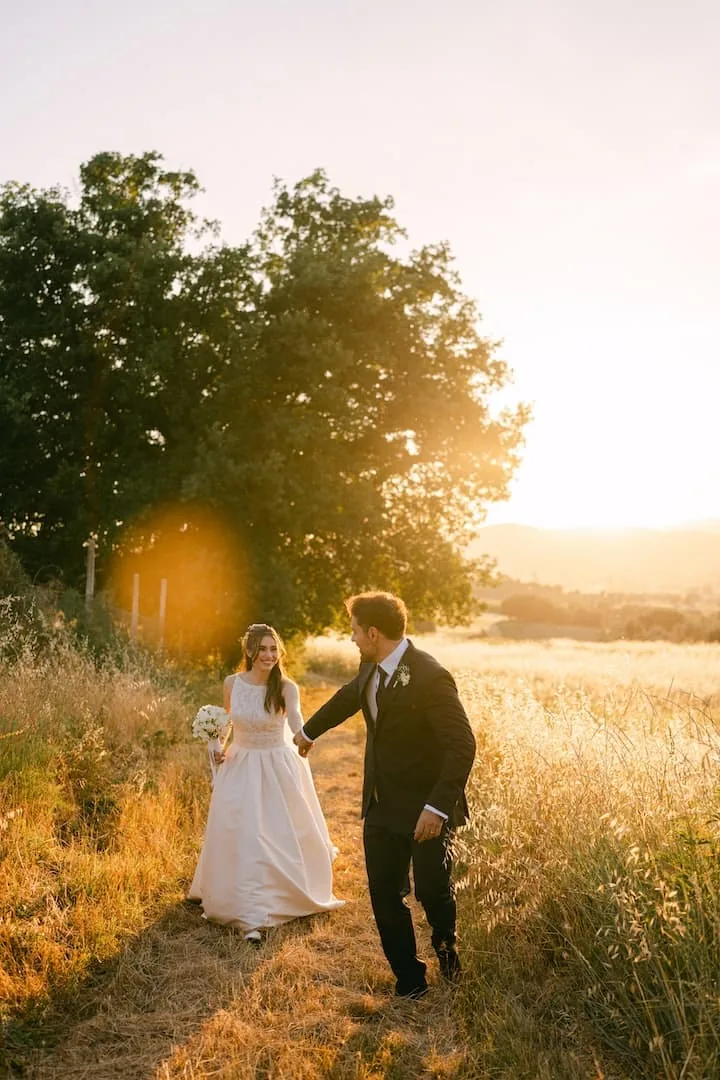 Couple walking through a golden field at sunset in the Umbrian countryside