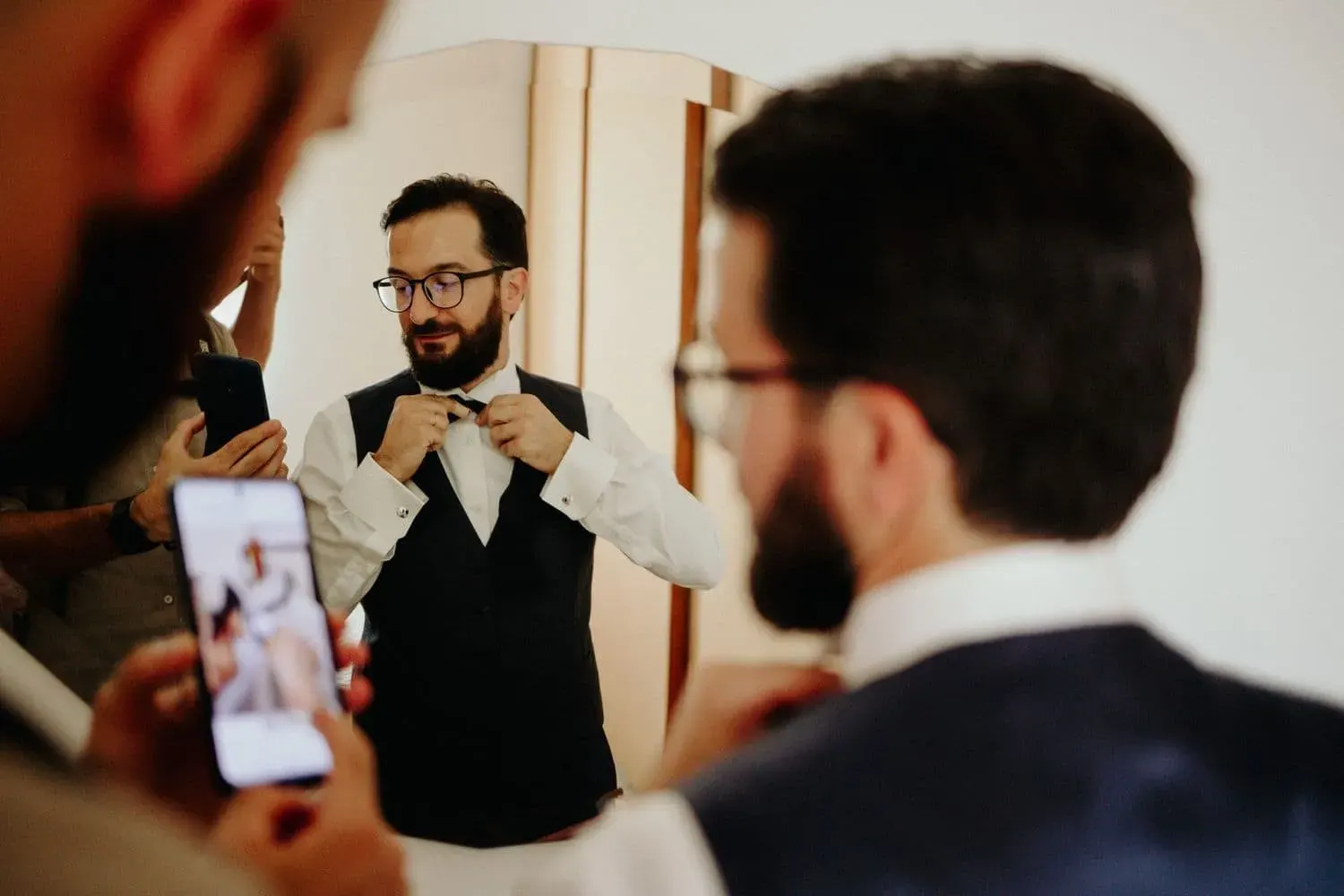 Un amico fotografa lo sposo mentre si sistema il papillon