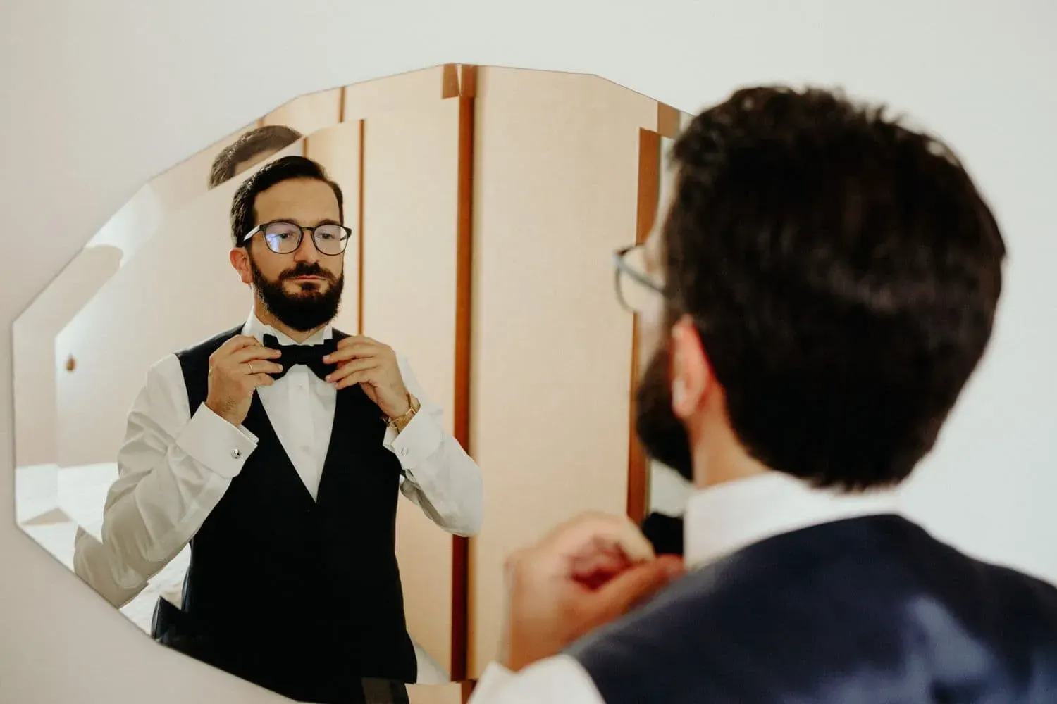 Lo sposo si sistema il papillon davanti allo specchio