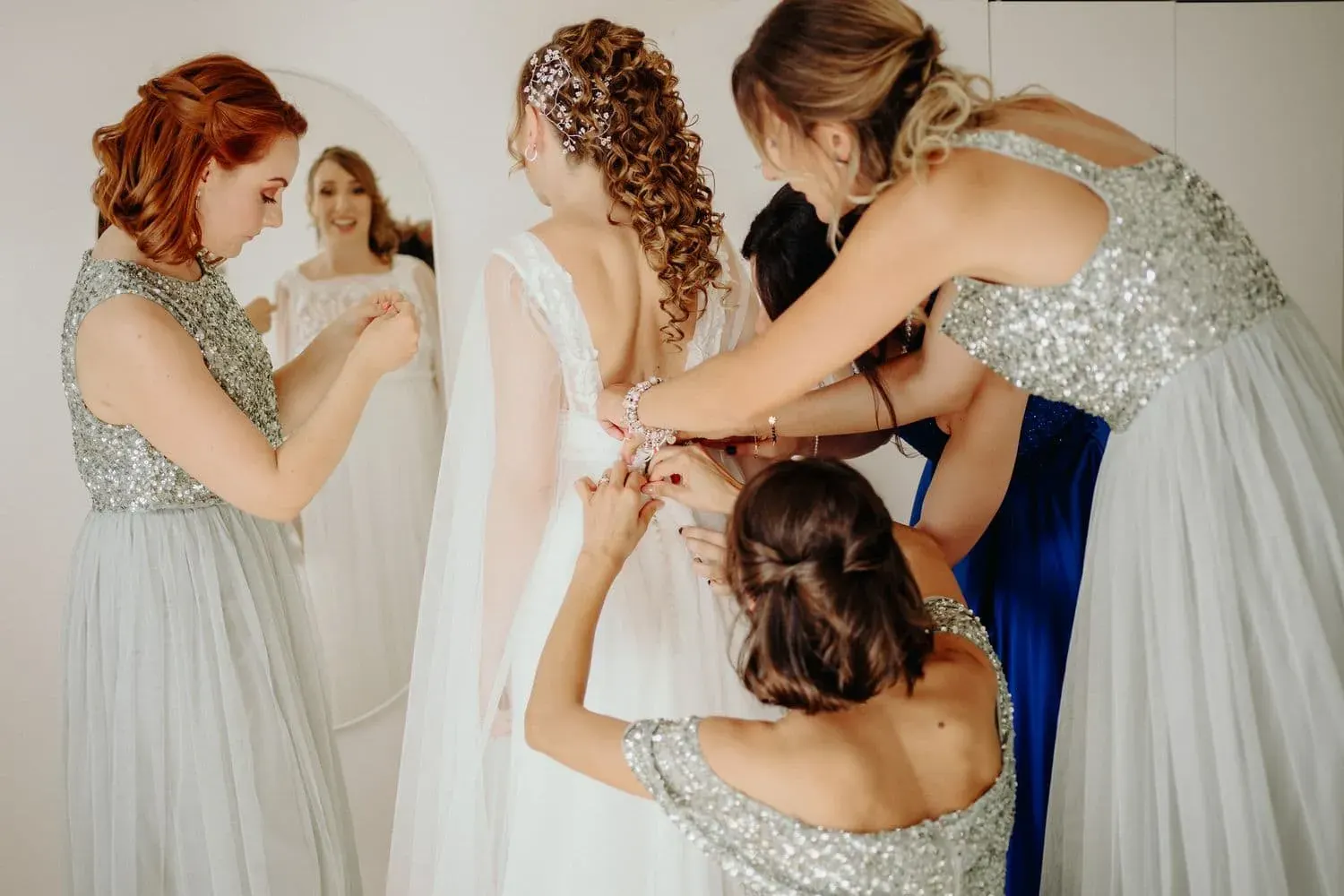 Le damigelle in abito salvia aiutano la sposa a vestirsi