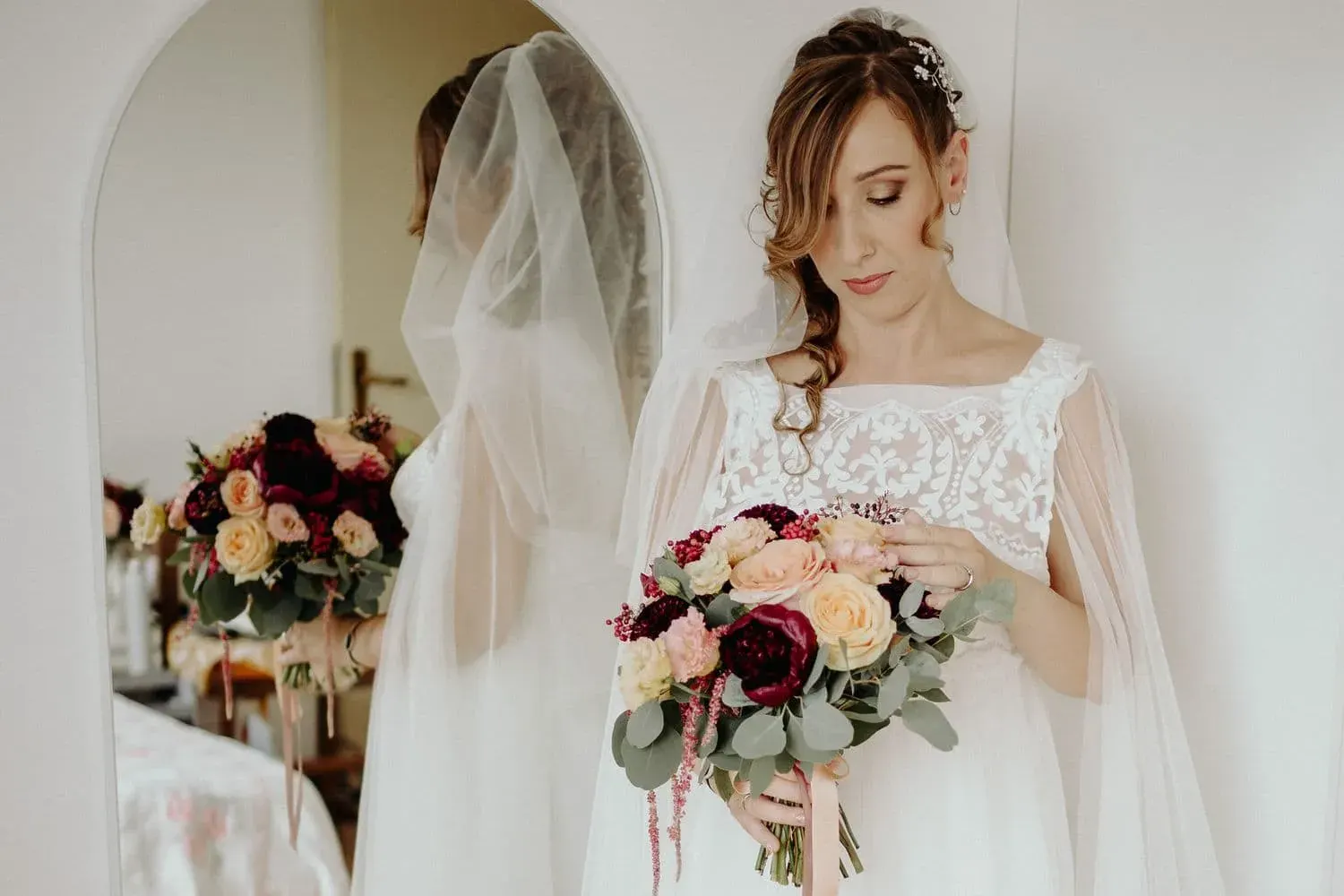 La sposa con velo e bouquet nei toni del pesca e del bordeaux