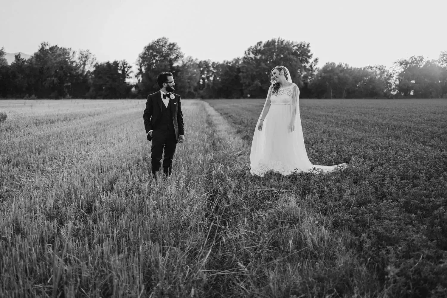 Gli sposi a distanza in un campo verde, in bianco e nero