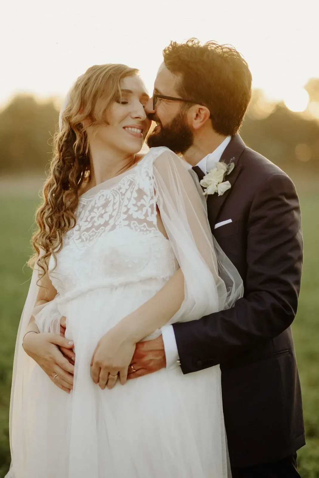Lo sposo abbraccia la sposa nel campo al tramonto