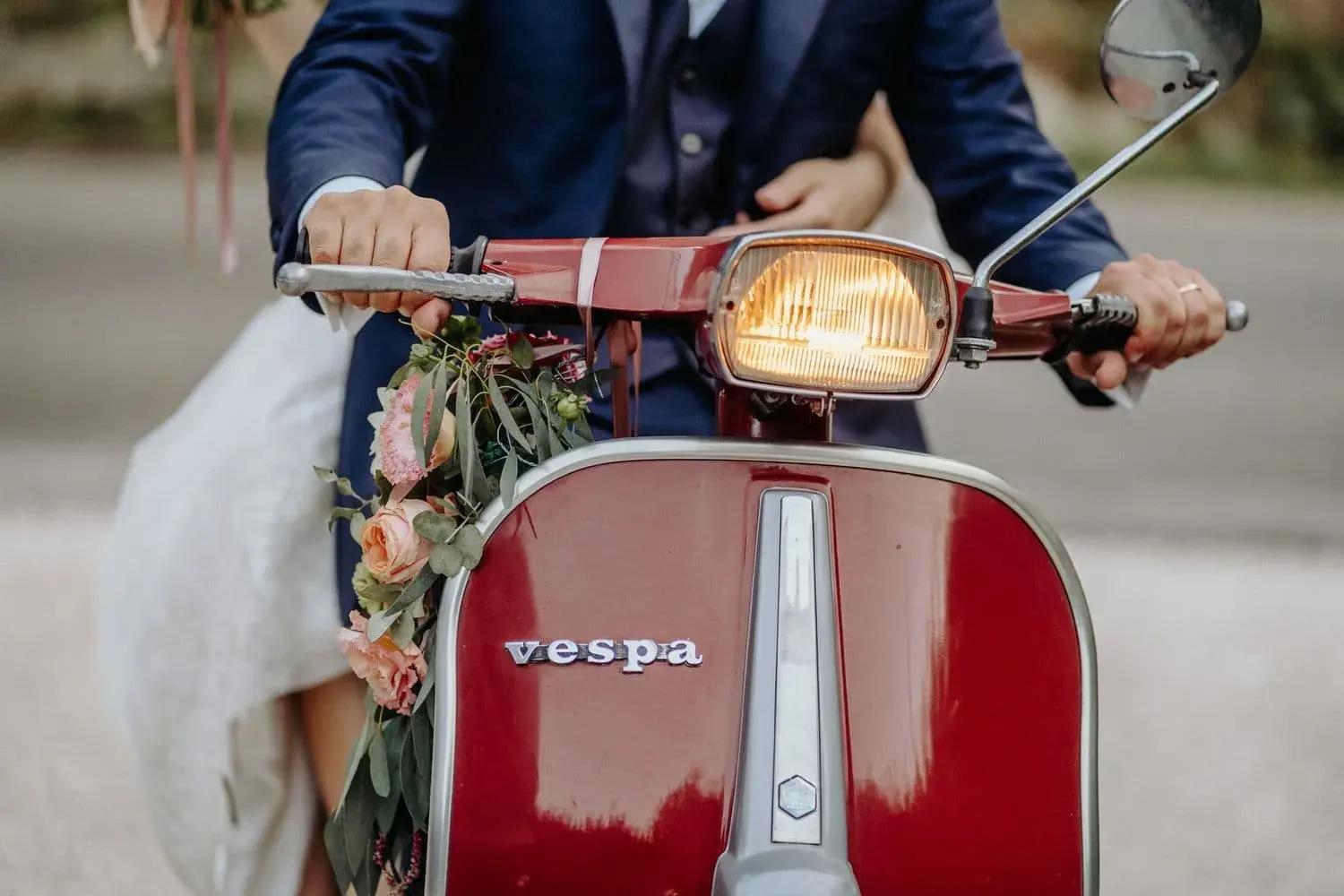 Dettaglio della Vespa rossa d'epoca con lo sposo alla guida