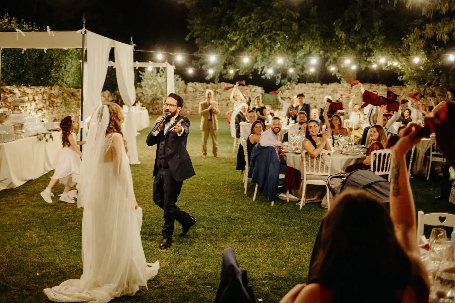 La sposa cammina tra i tavoli sotto le luci