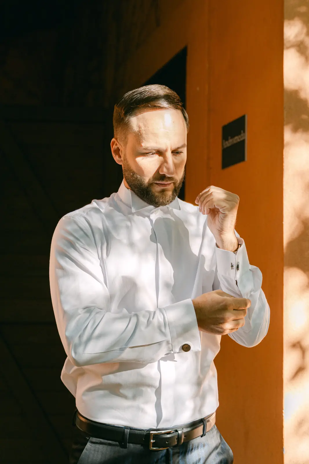 The groom getting ready, fastening his shirt cuffs