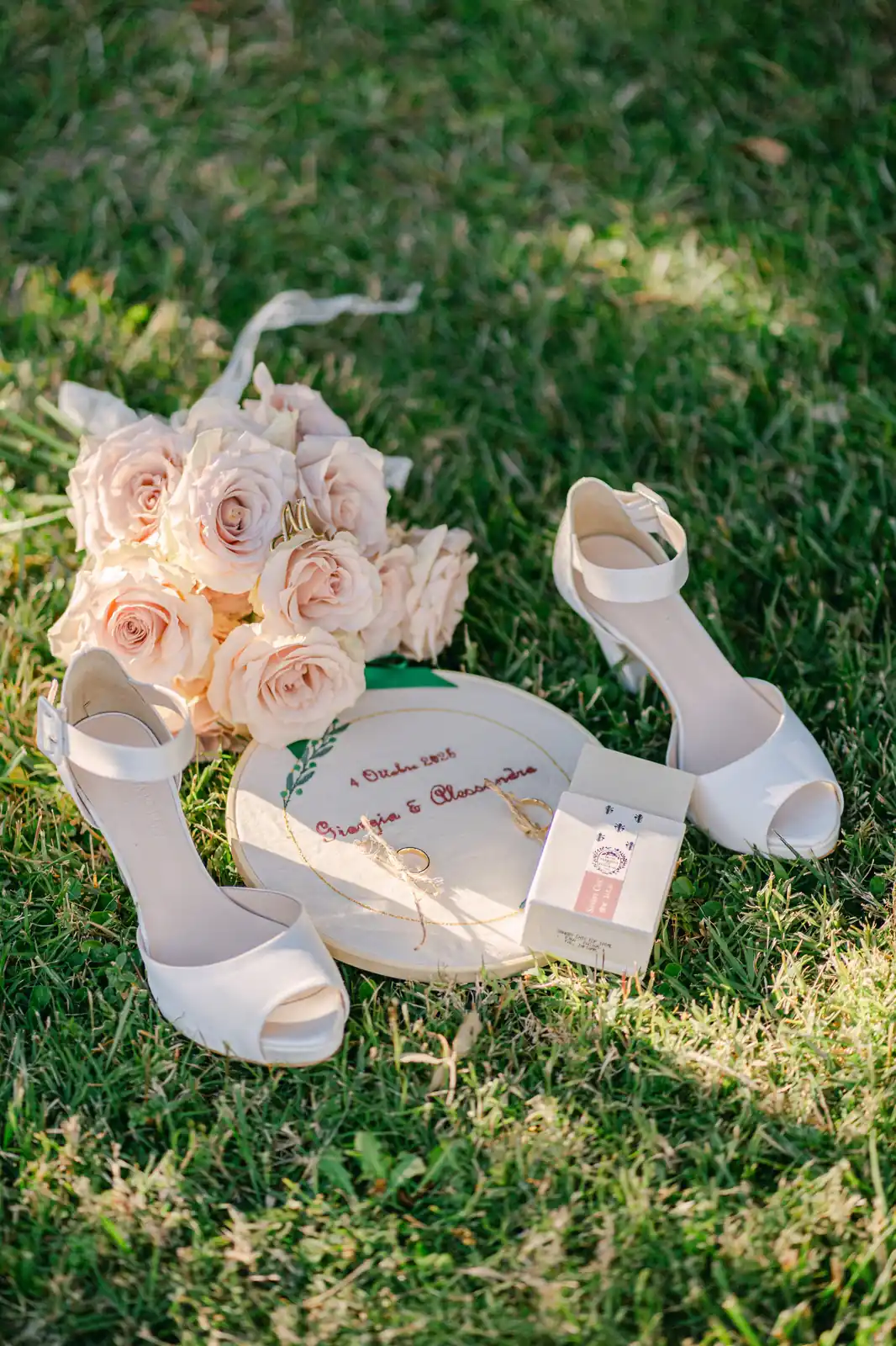The bride's shoes and rose bouquet resting on the lawn