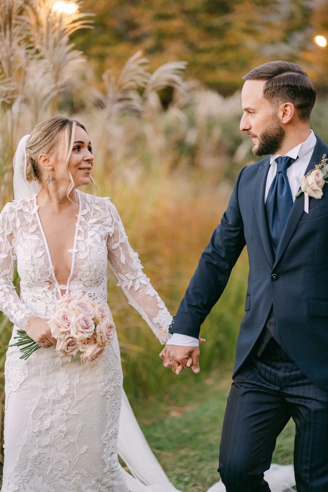 A portrait of the couple hand in hand among the pampas grass