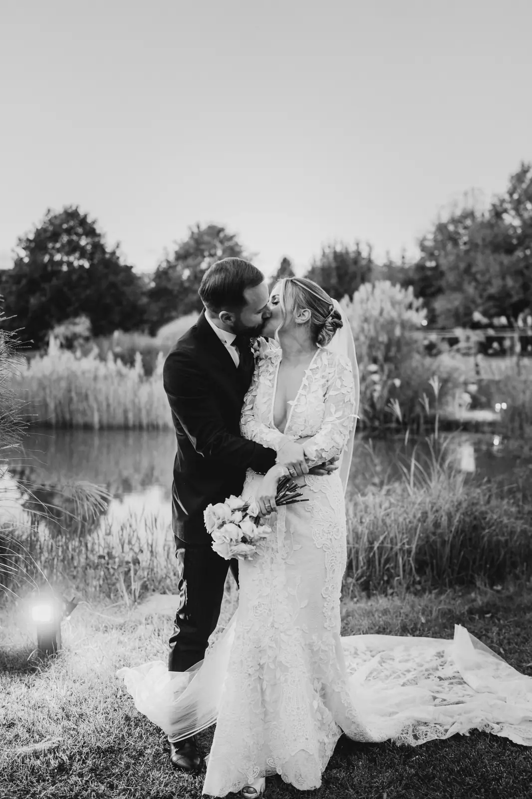 A black and white portrait of the couple by the small lake