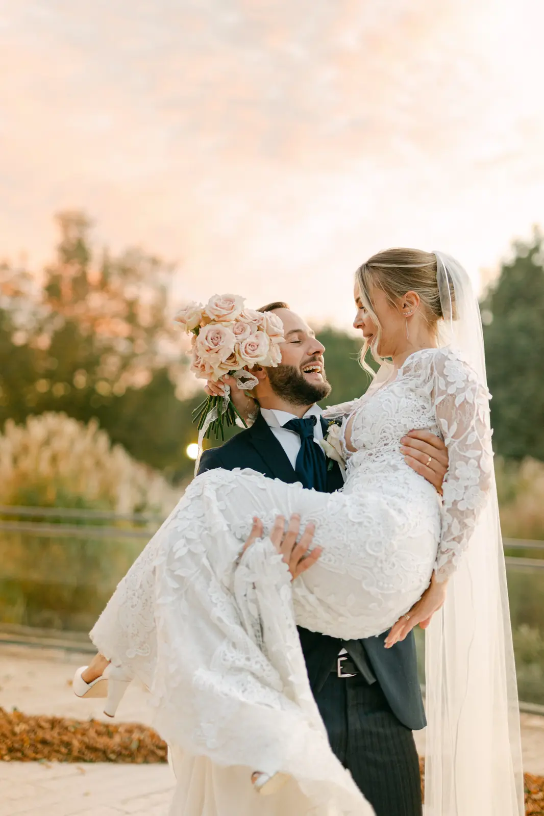 The groom lifting the bride against the sunset sky