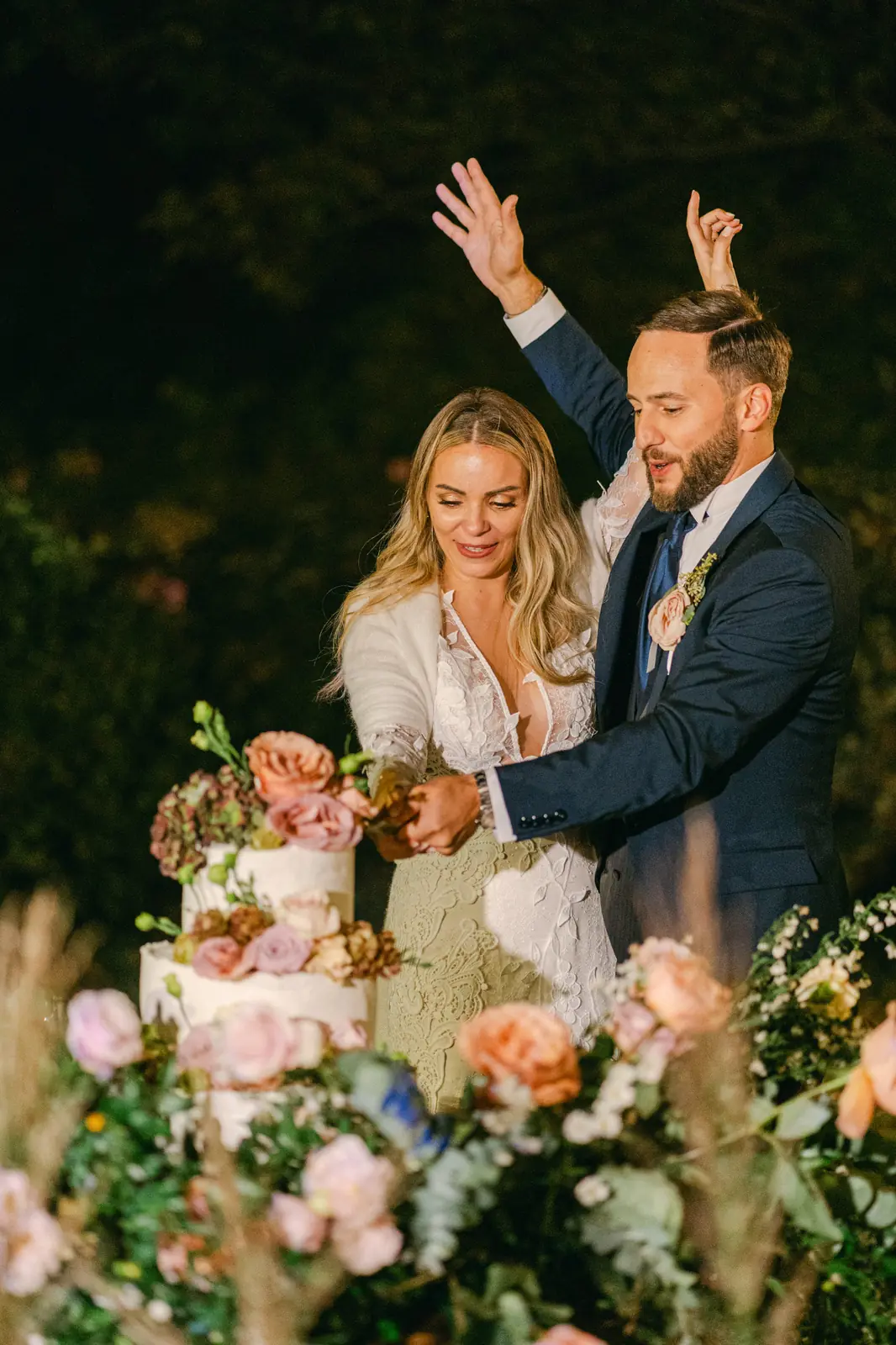 Cutting the wedding cake among the flowers
