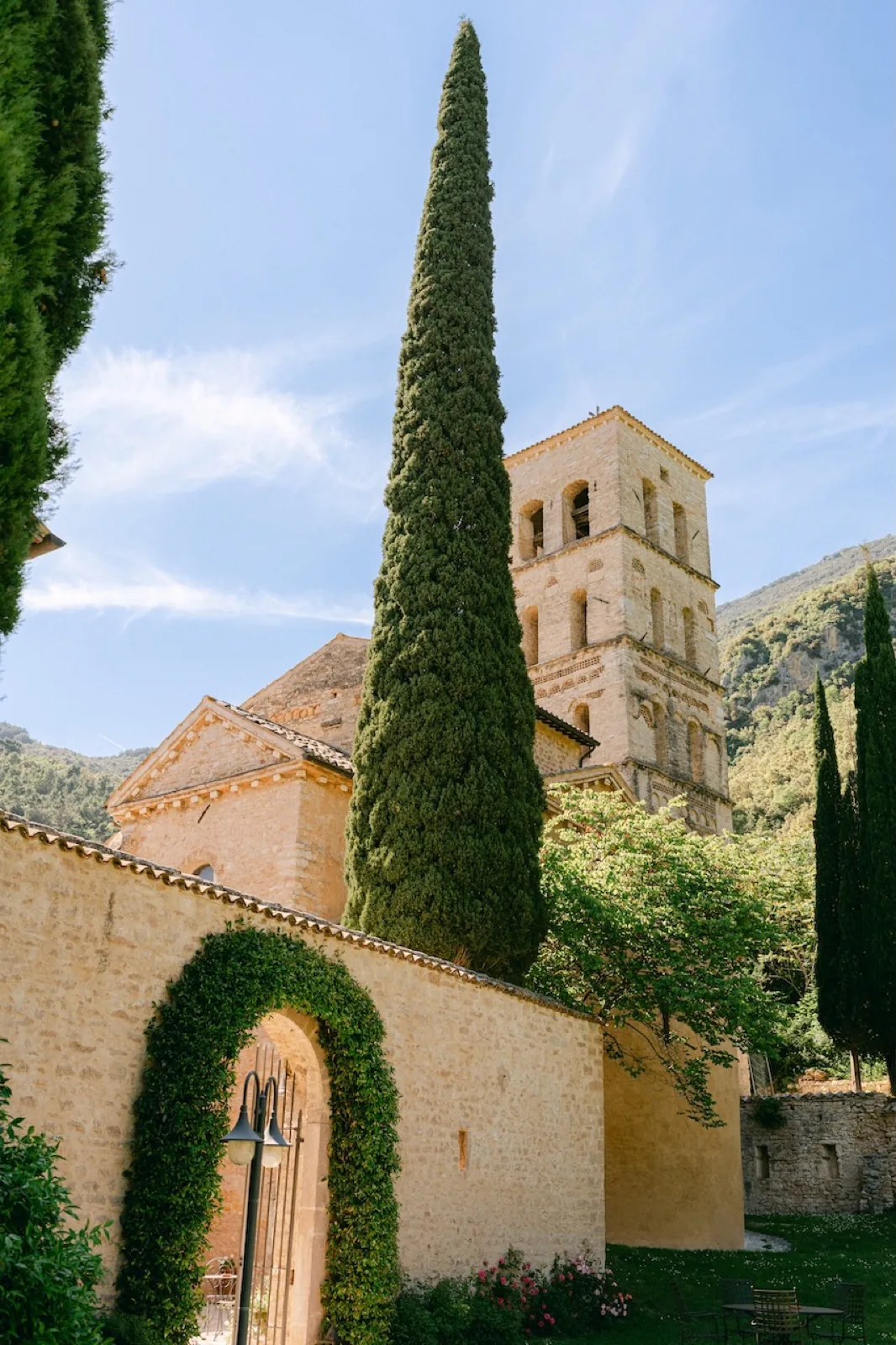 Il campanile romanico dell’Abbazia San Pietro in Valle tra i cipressi, con l’arco d’edera all’ingresso