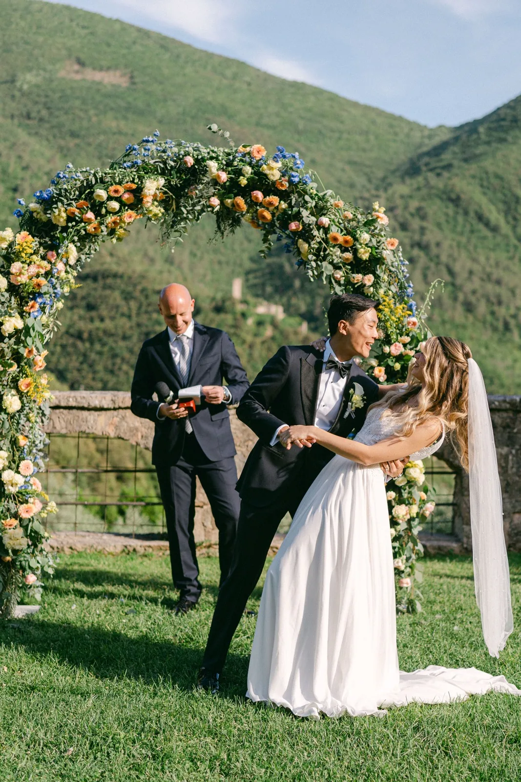 Il primo bacio da sposati sotto l’arco di fiori, nel giardino panoramico dell’abbazia