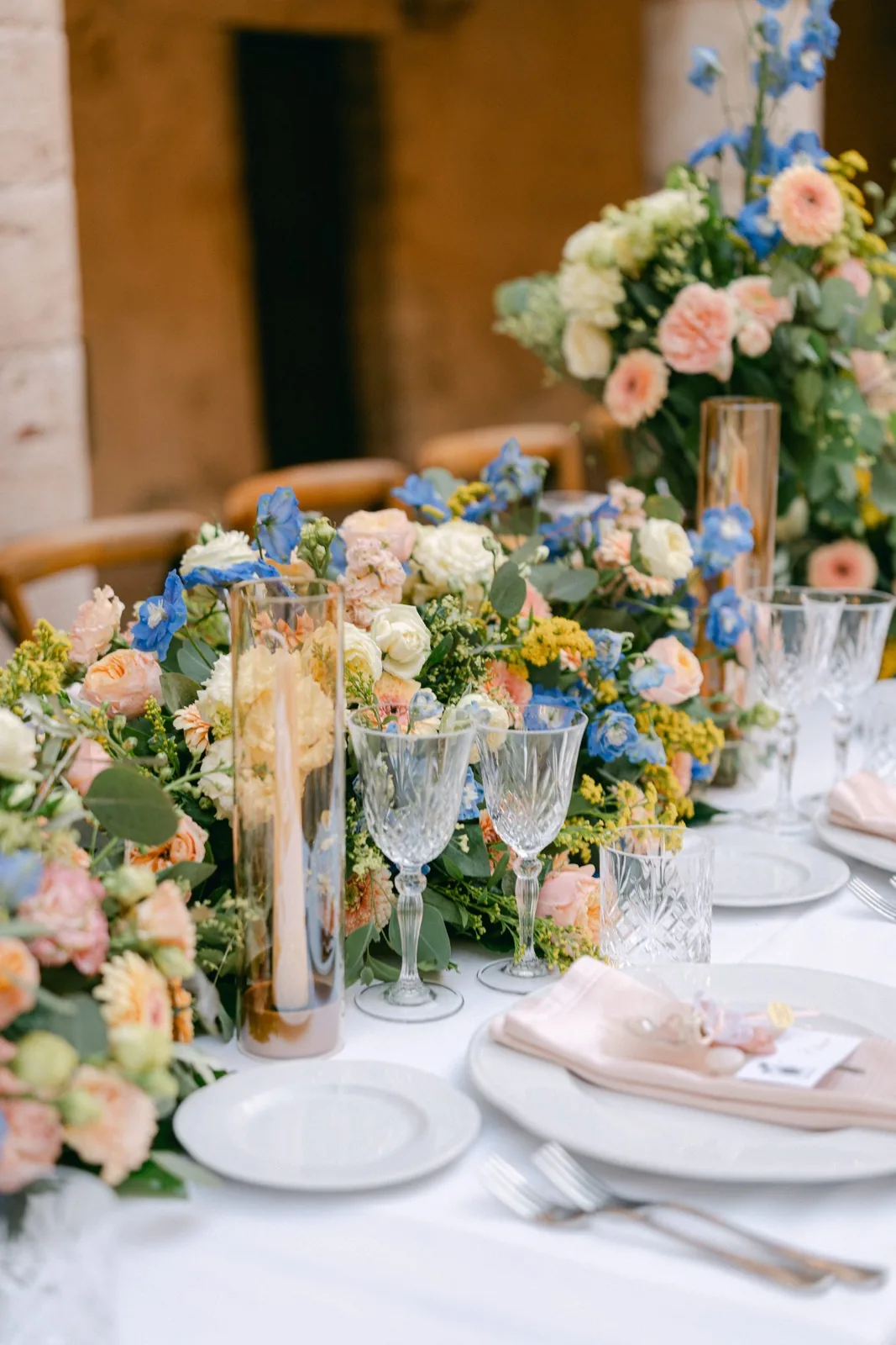 Dettaglio della mise en place: calici di cristallo, fiori e tovaglioli rosa cipria