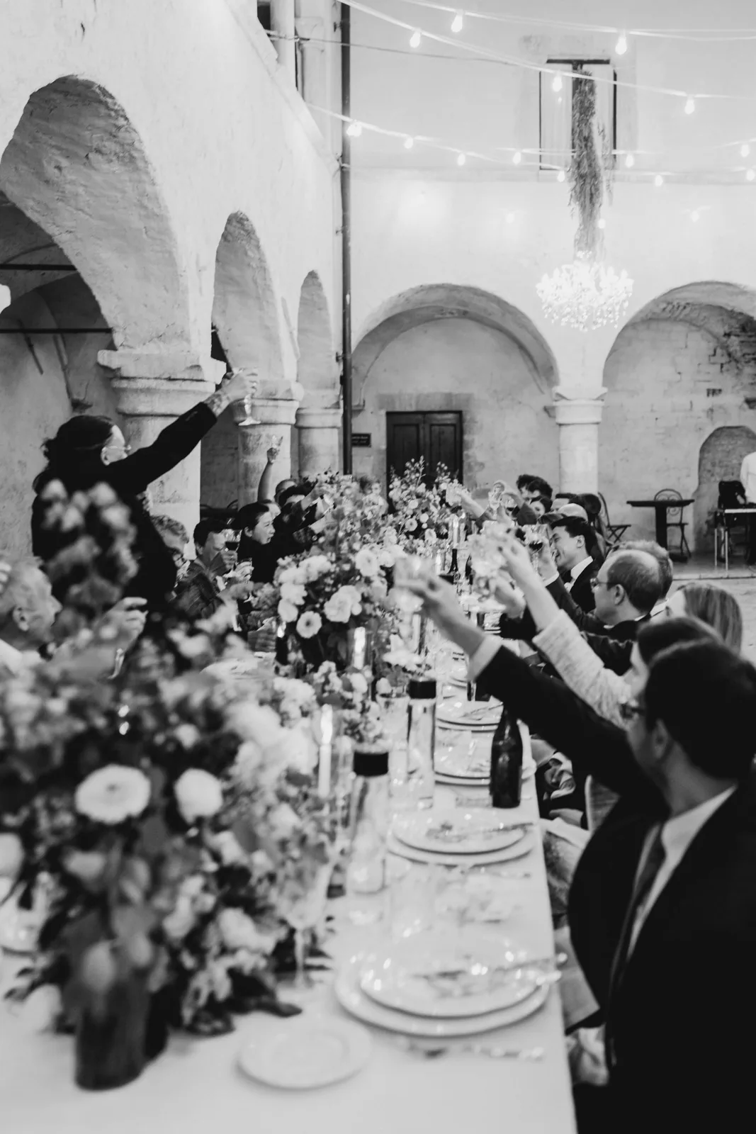 Il brindisi degli invitati durante la cena nel chiostro, in bianco e nero