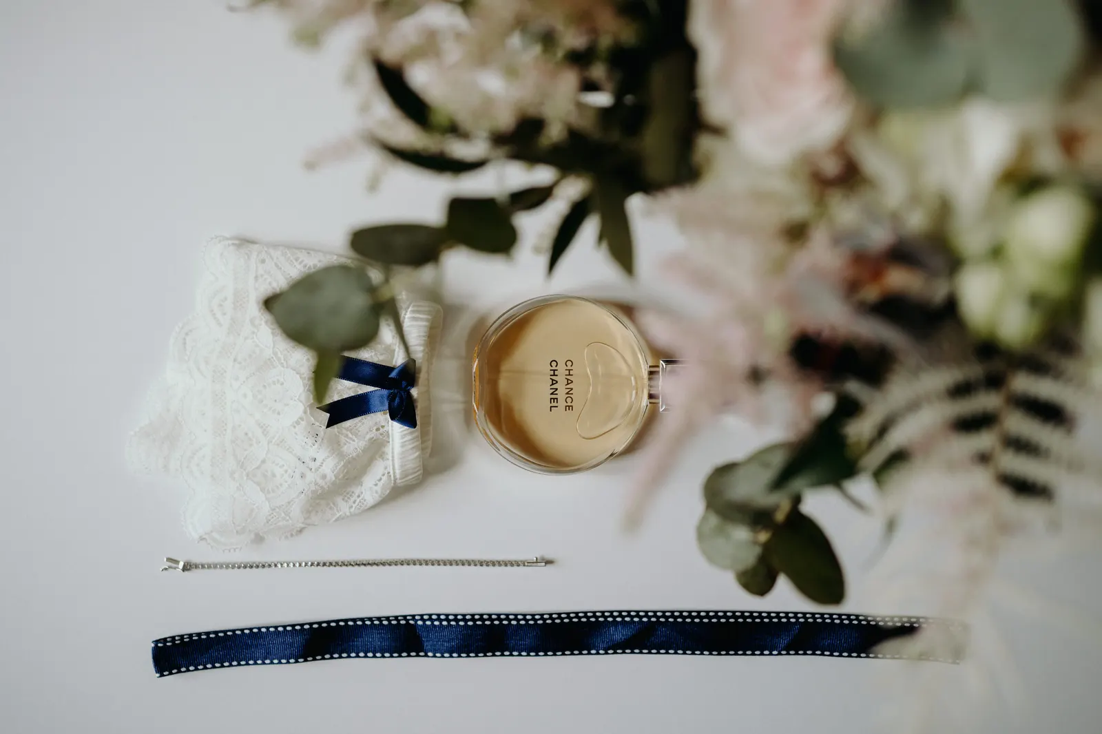 Lace garter, perfume, bracelet and bouquet flowers: the bride's details