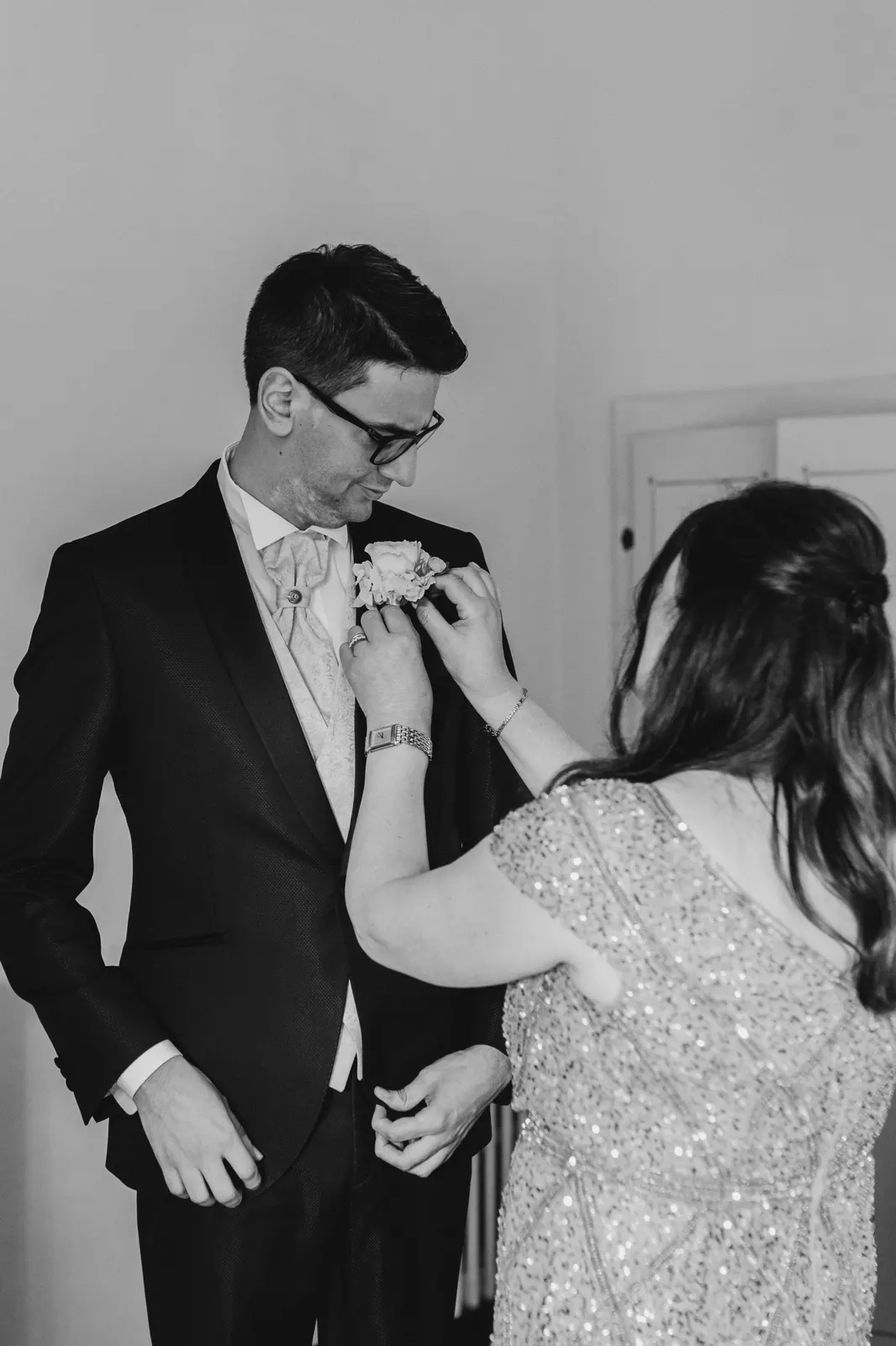 Daniele smiling as his buttonhole is pinned on, in black and white