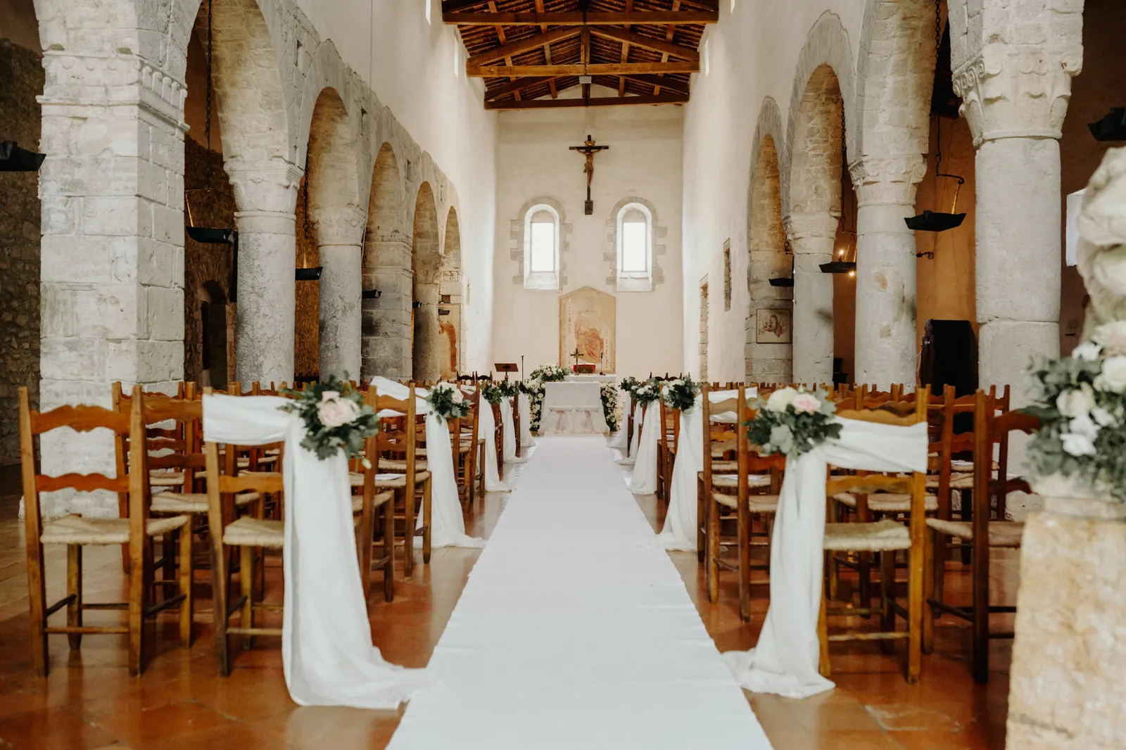 The nave of the church of San Nicolò in San Gemini with a white aisle runner and flowers
