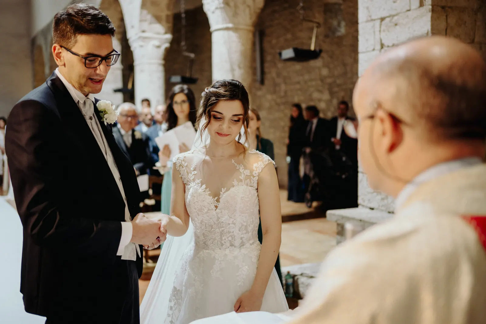 The couple holding hands in front of the priest during the ceremony