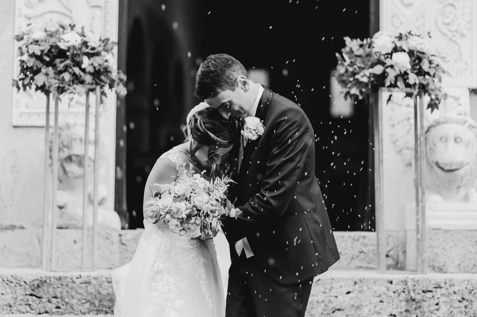 The couple kissing outside the church among the rice, in black and white