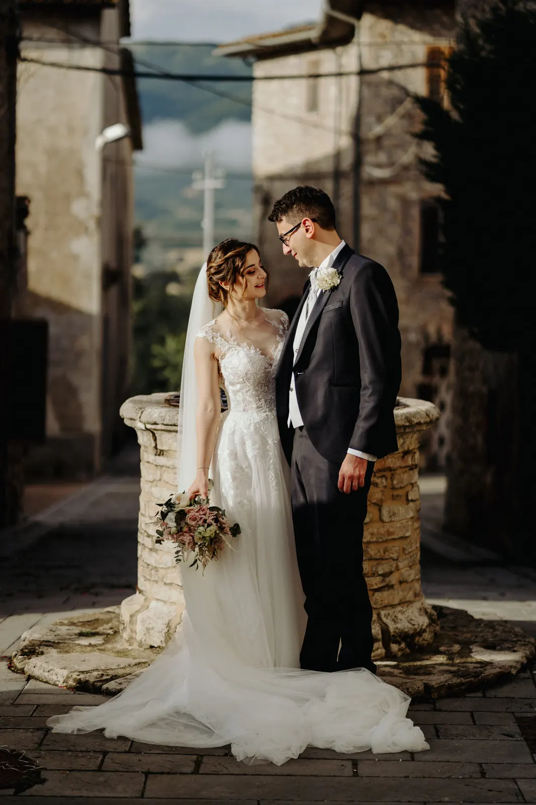 The couple beside the stone well among the houses of the Montignano hamlet