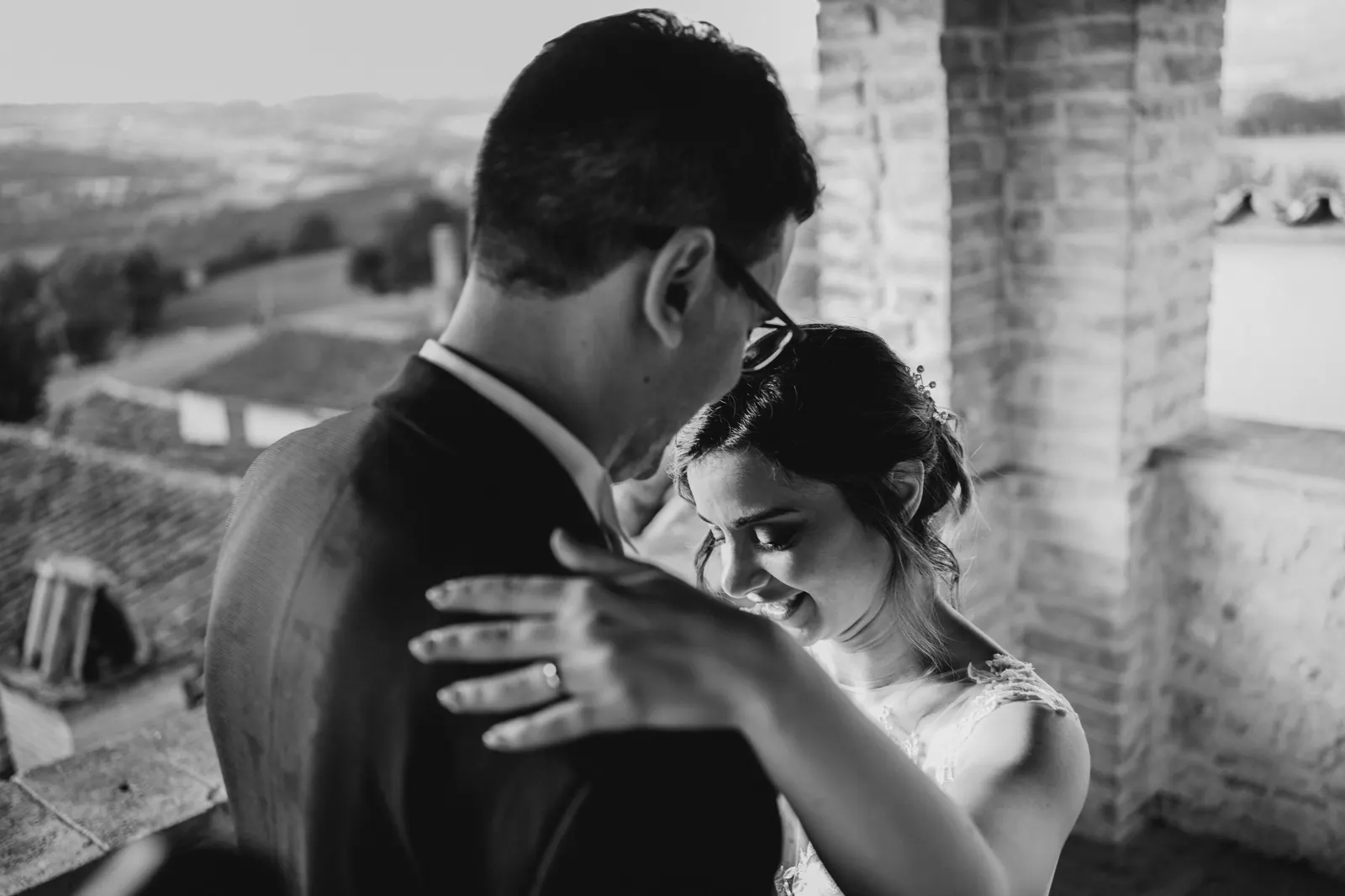 The couple embracing with rooftops and the Umbrian hills behind, in black and white