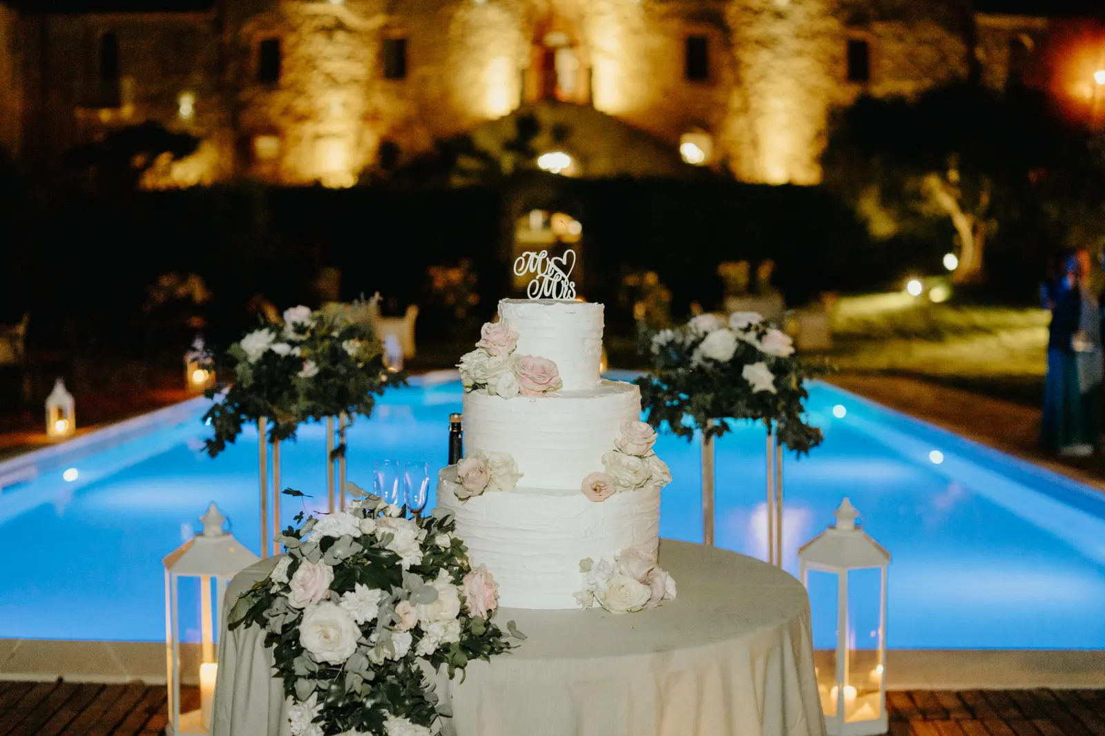 The wedding cake by the pool, with the castle walls lit up in the evening