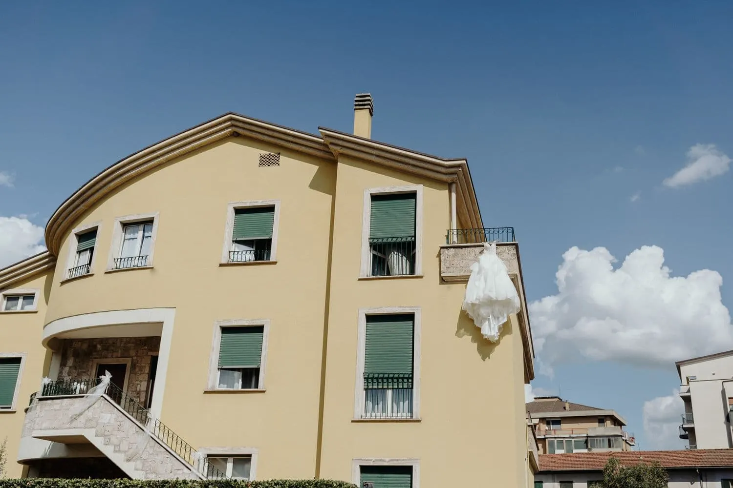 La casa di Micaela con l'abito da sposa appeso al balcone, sotto il cielo azzurro