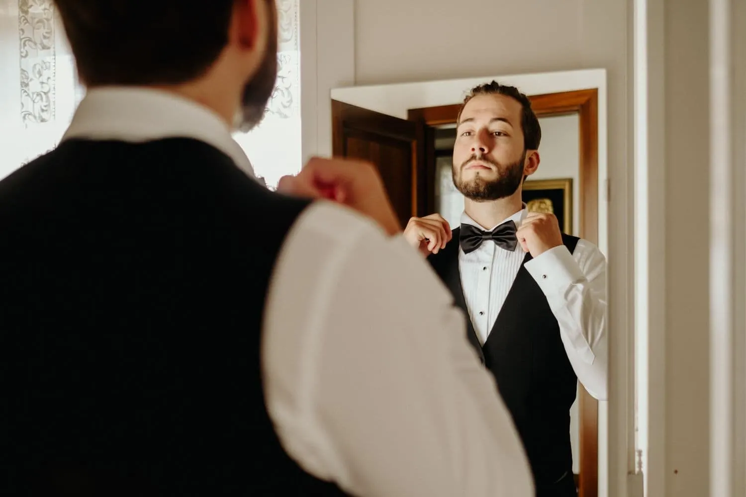 Raffaele adjusting his bow tie in the mirror