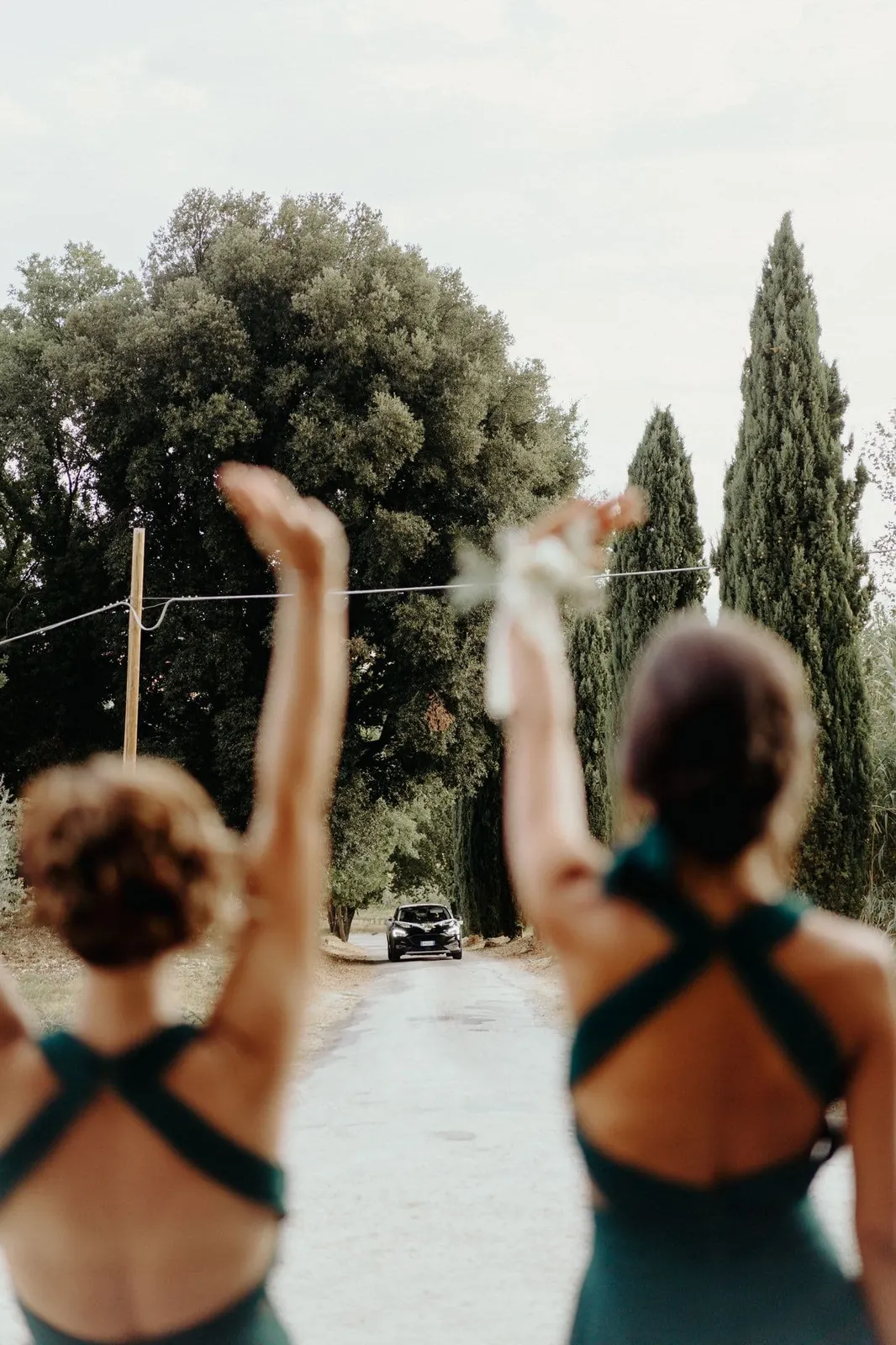 Le damigelle di spalle salutano a braccia alzate l'arrivo della sposa