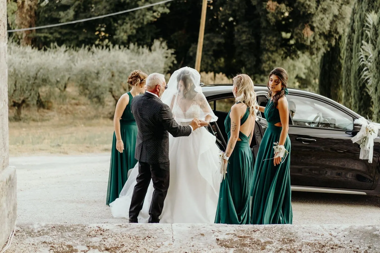 Micaela scende dall'auto aiutata dal padre e dalle damigelle