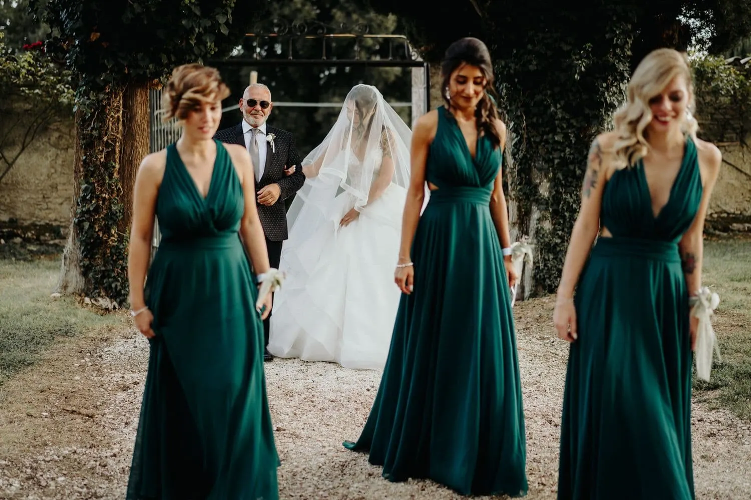 Le damigelle in verde bosco precedono la sposa lungo il viale