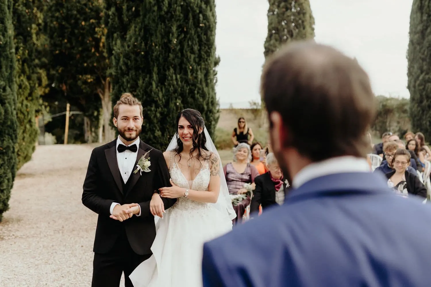 Gli sposi a braccetto ascoltano un amico durante la cerimonia