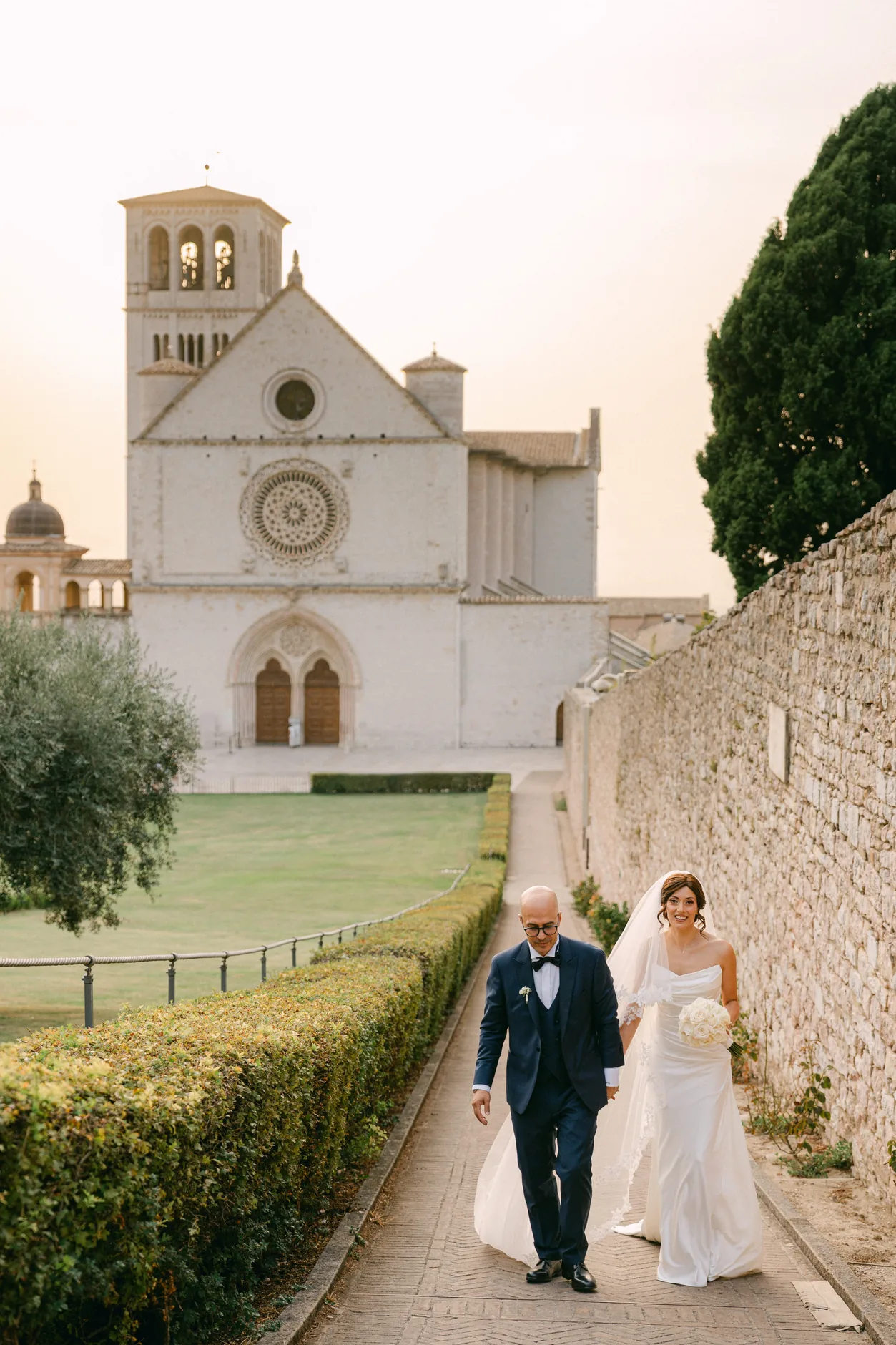 Rossella e Tonino camminano lungo il viale con la Basilica di San Francesco alle spalle