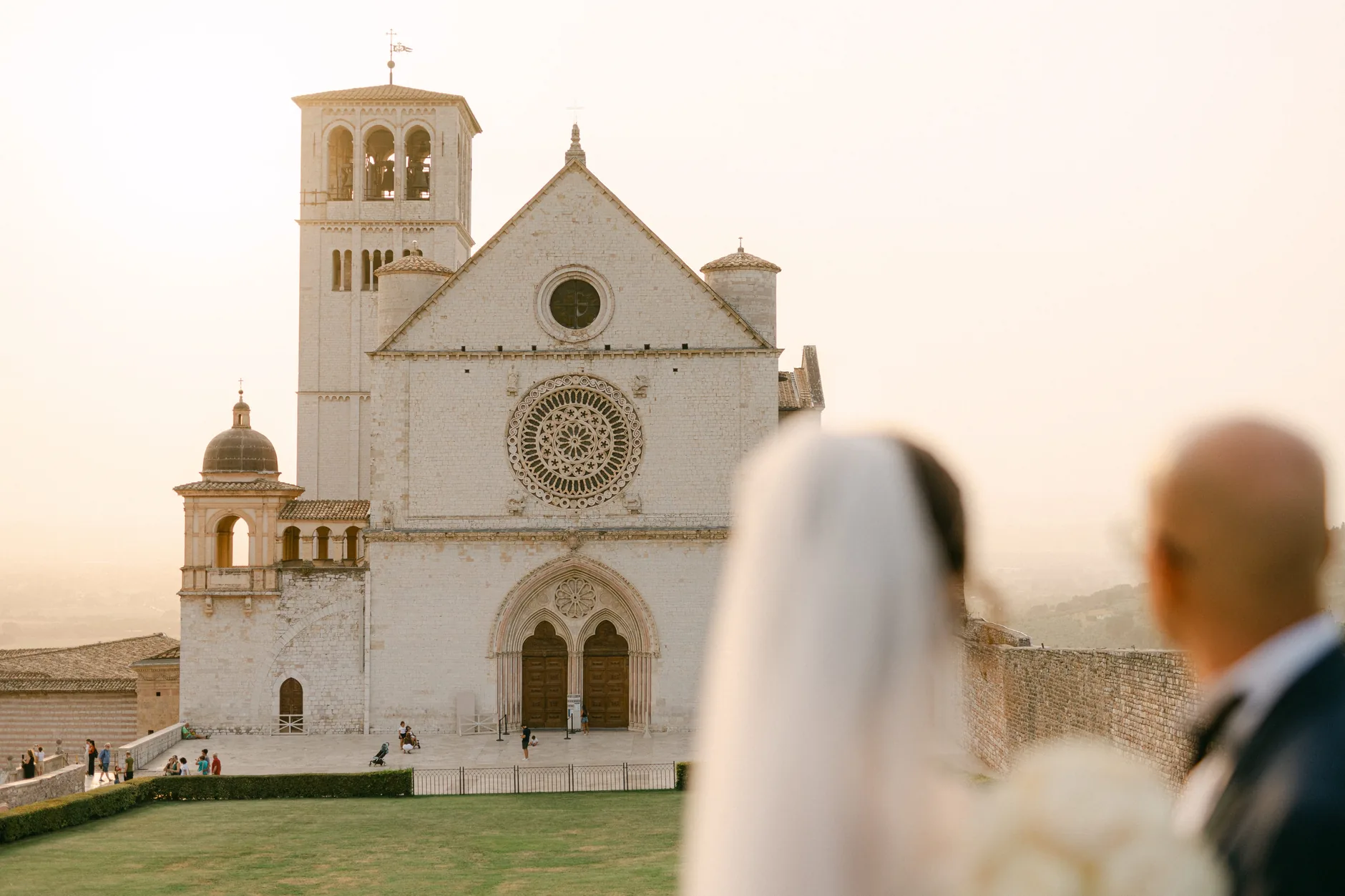 Gli sposi di spalle guardano la Basilica di San Francesco al tramonto