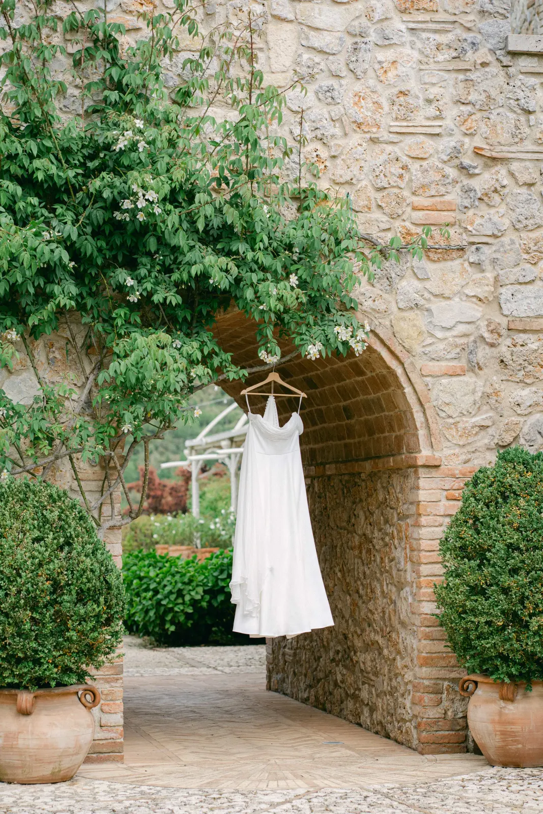 Audrey's dress hanging in the stone archway among the plants