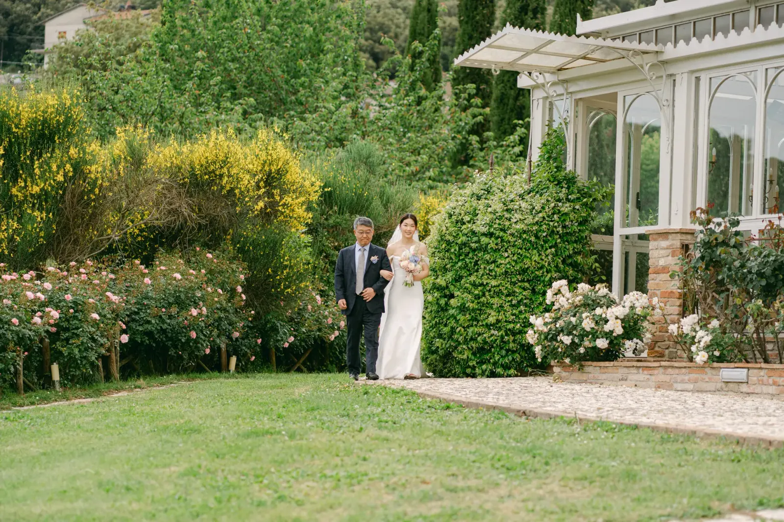 Audrey arriving at the ceremony on her father's arm, beside the conservatory