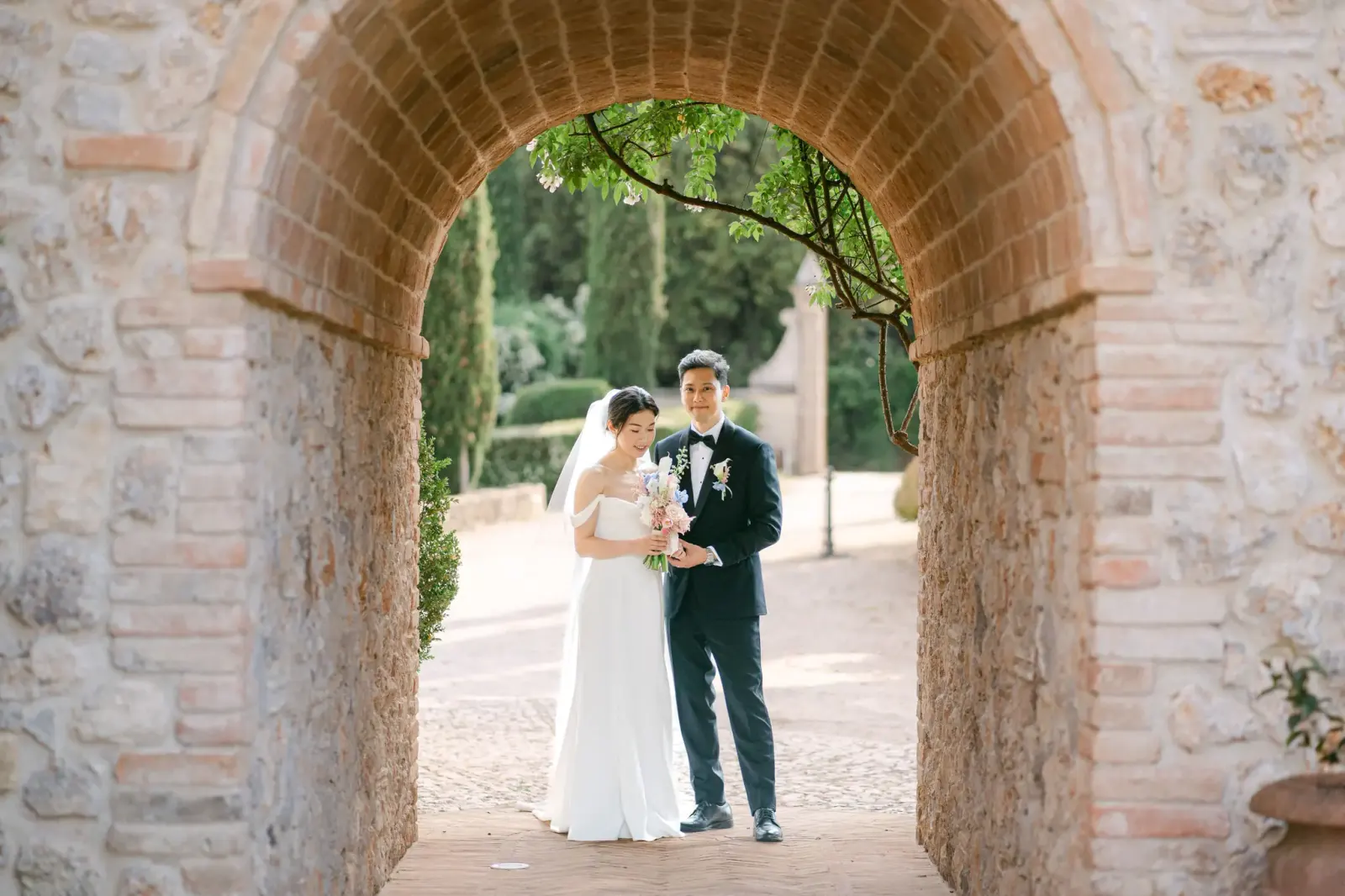 The couple framed by a brick and stone archway on the estate