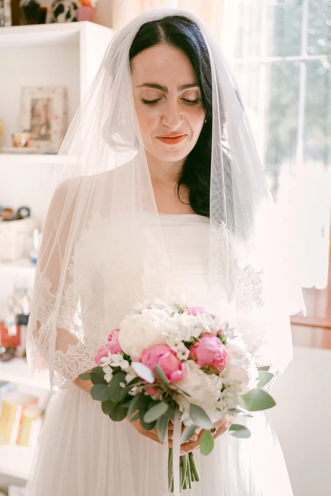 Valentina con il velo sul capo e il bouquet di peonie rosa e bianche