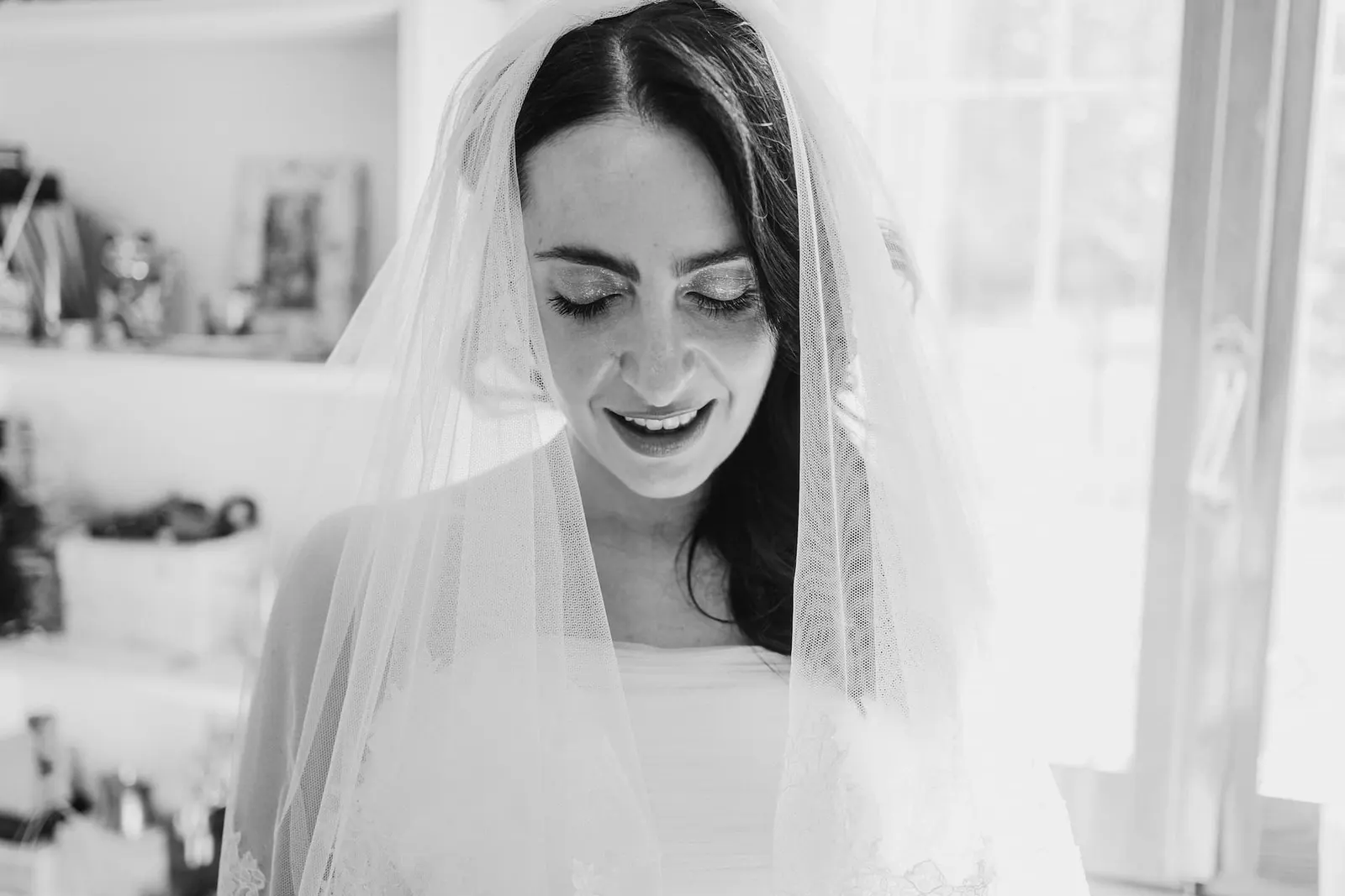 La sposa sorride sotto il velo, in bianco e nero
