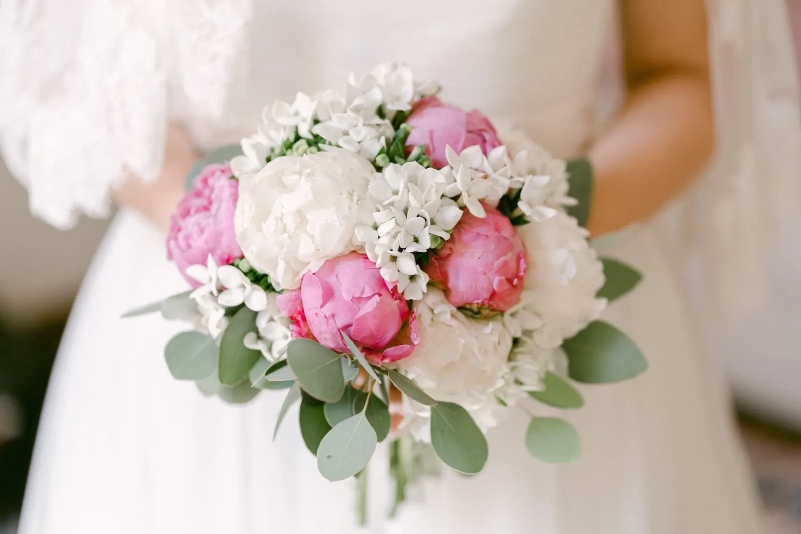 Il bouquet di peonie rosa e bianche tra le mani della sposa