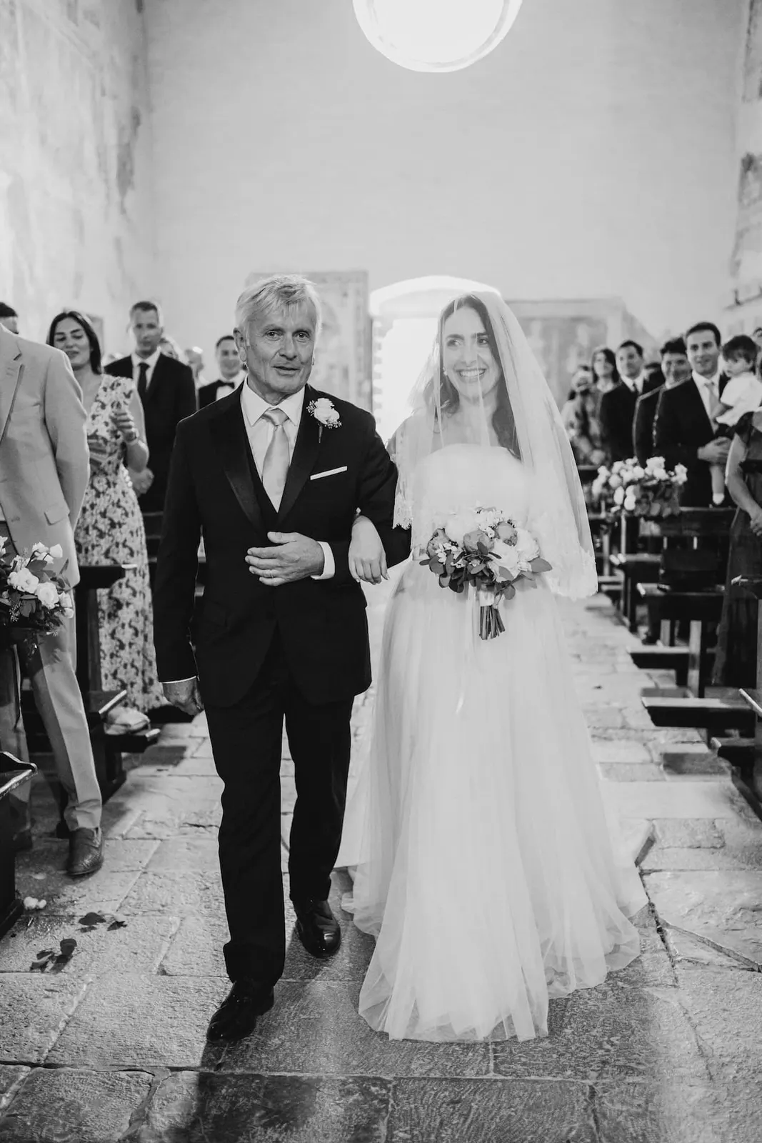 Valentina percorre la navata al braccio del padre, in bianco e nero
