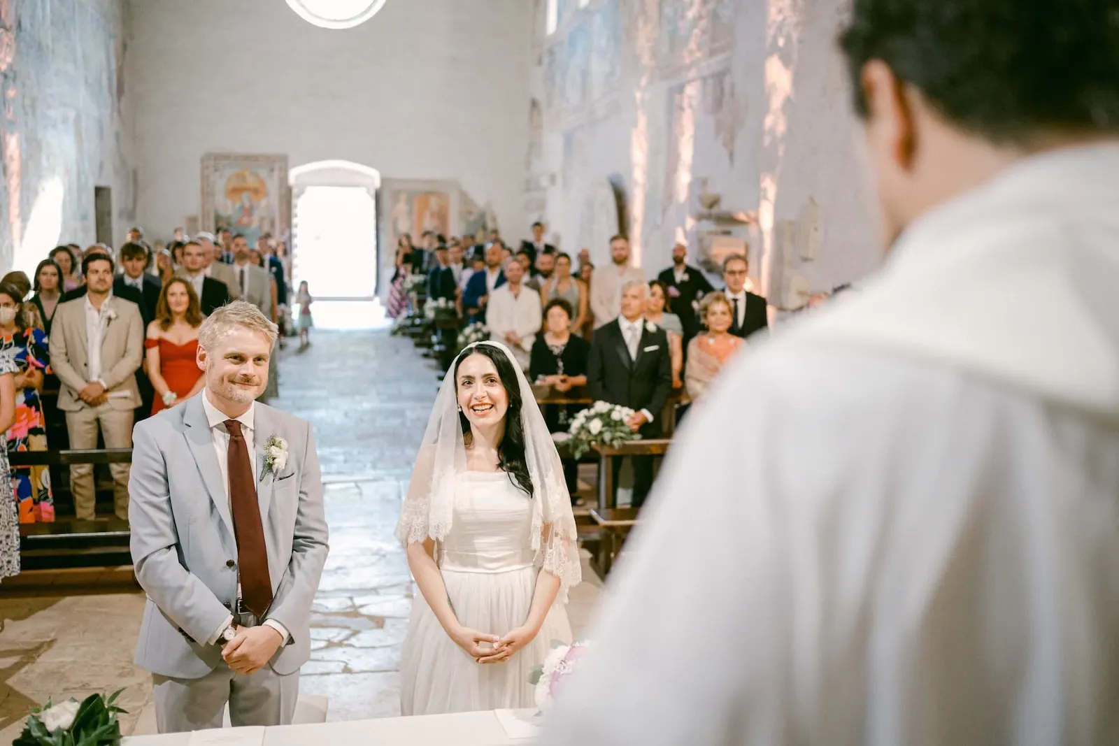 Gli sposi in piedi davanti all'altare, con gli invitati alle spalle
