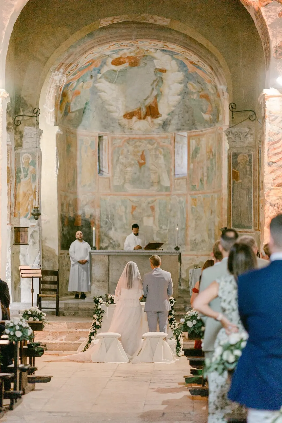 Gli sposi seduti davanti all'altare sotto l'abside affrescata