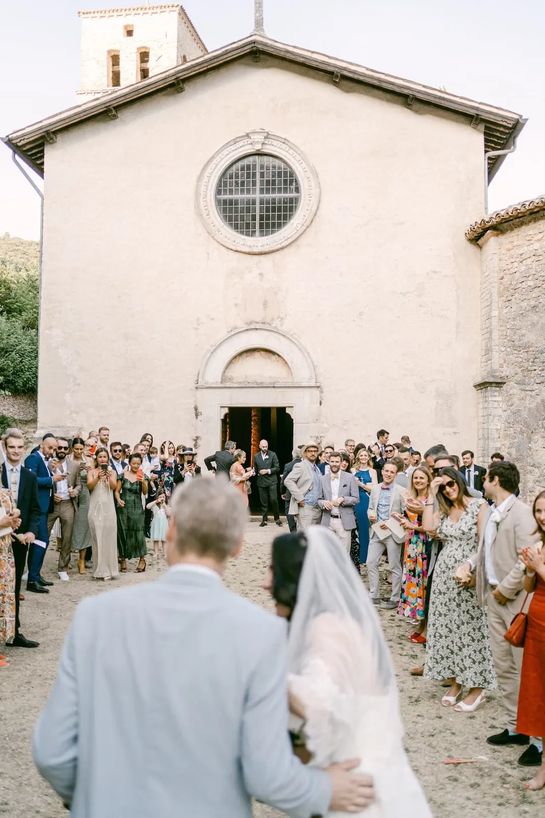 Gli sposi di spalle davanti agli invitati riuniti sul sagrato dell'abbazia