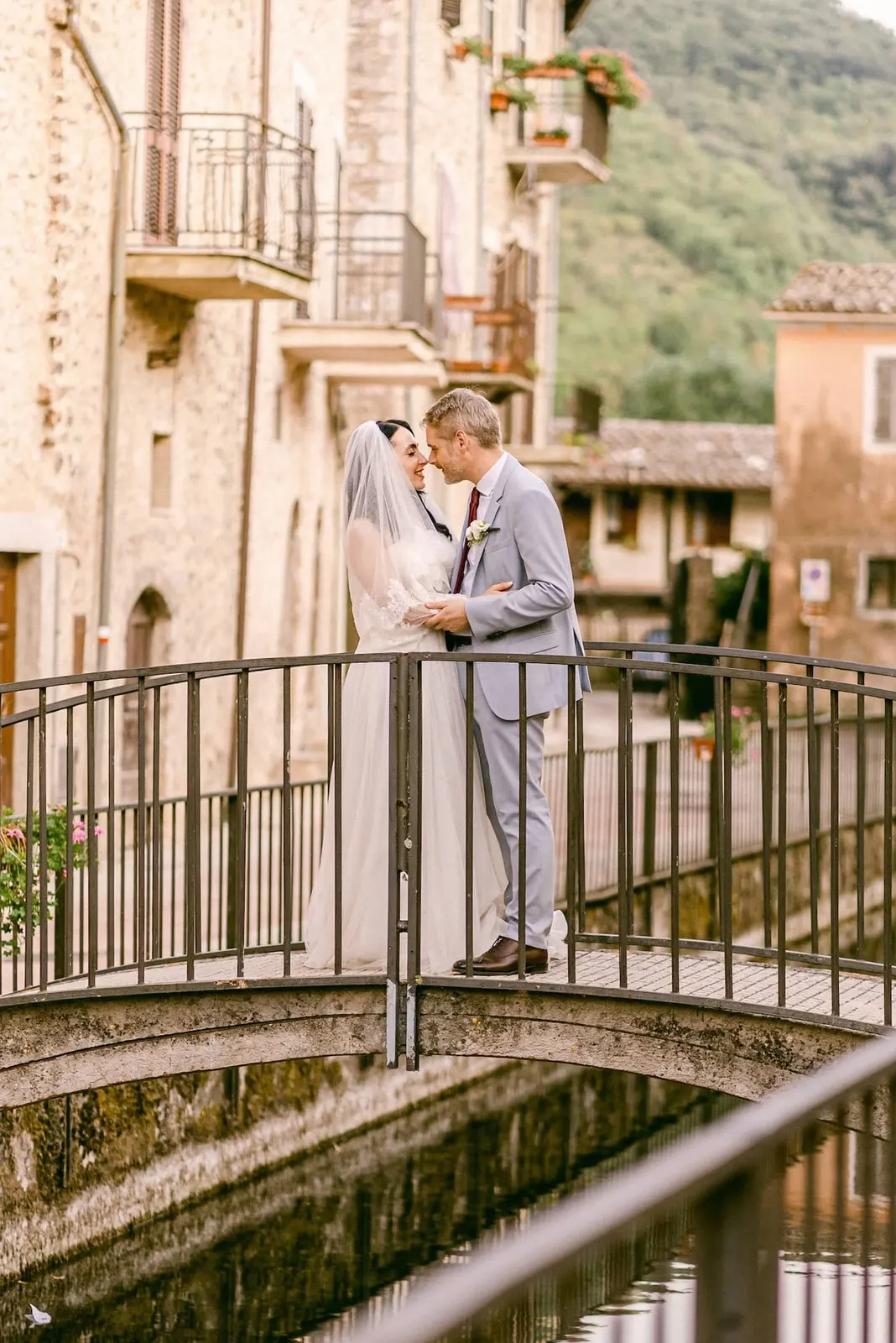 Gli sposi si baciano su un ponticello tra le case in pietra del borgo