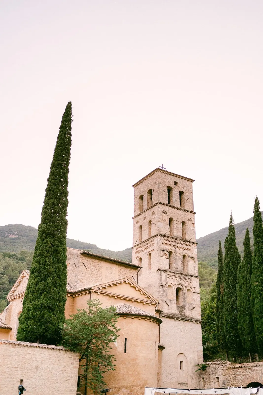 Il campanile dell'abbazia tra i cipressi al tramonto
