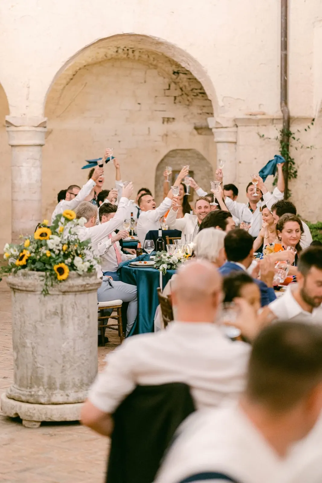 Gli invitati sventolano i tovaglioli tra i tavoli del chiostro