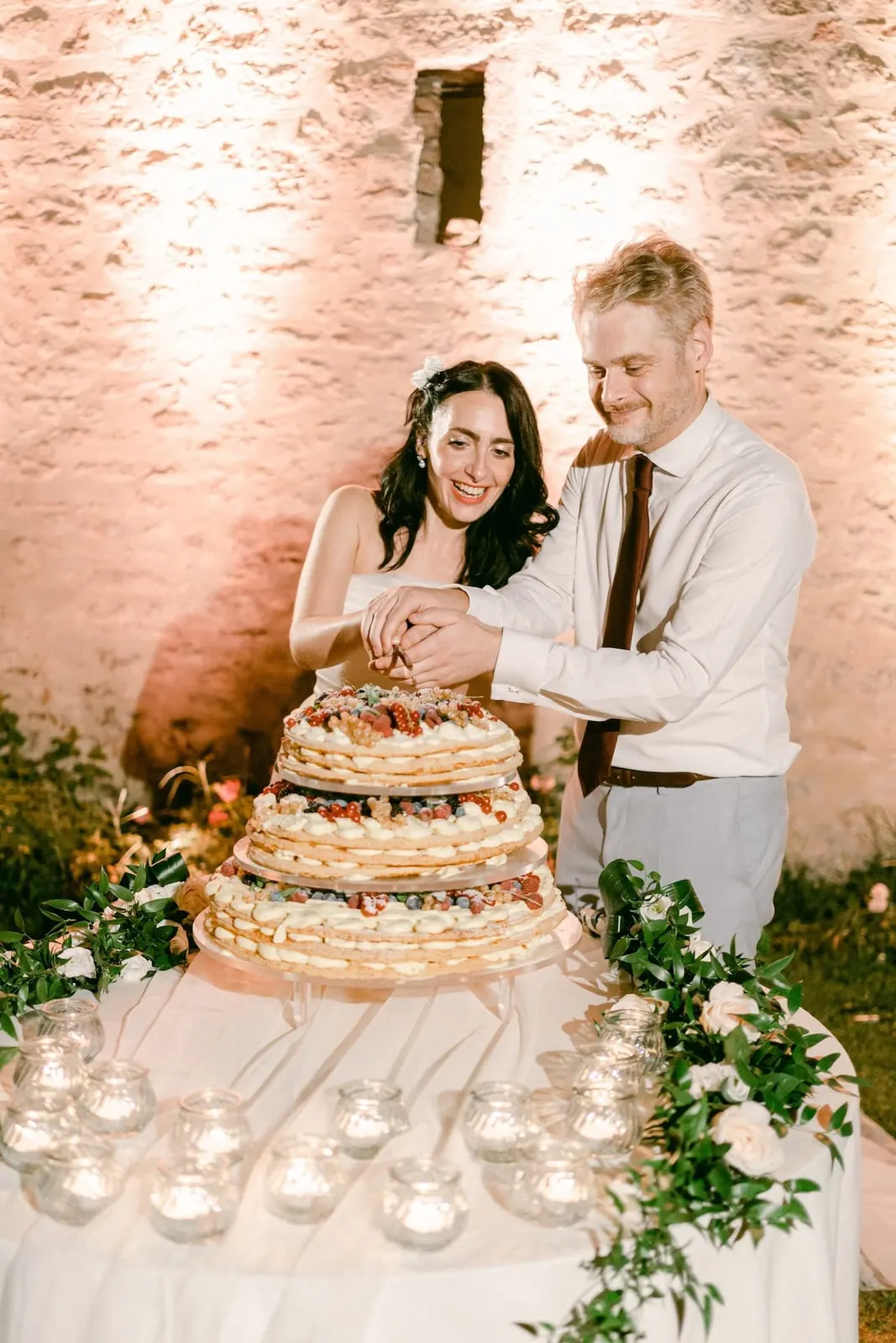 Valentina e Thomas tagliano la torta contro il muro illuminato dell'abbazia