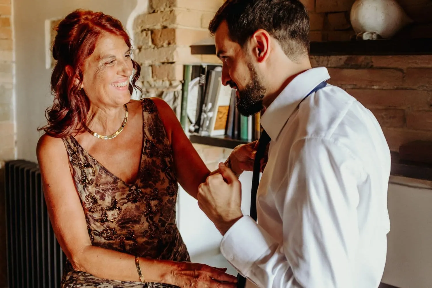 Francesco knotting his tie and sharing a smile while getting ready